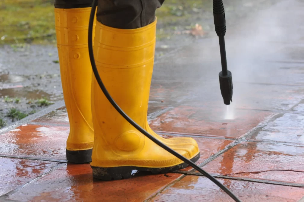 person wearing yellow rubber boots with high pressure water nozzle cleaning dirt tiles min Value Maids - New South Wales | Become Your Own Boss